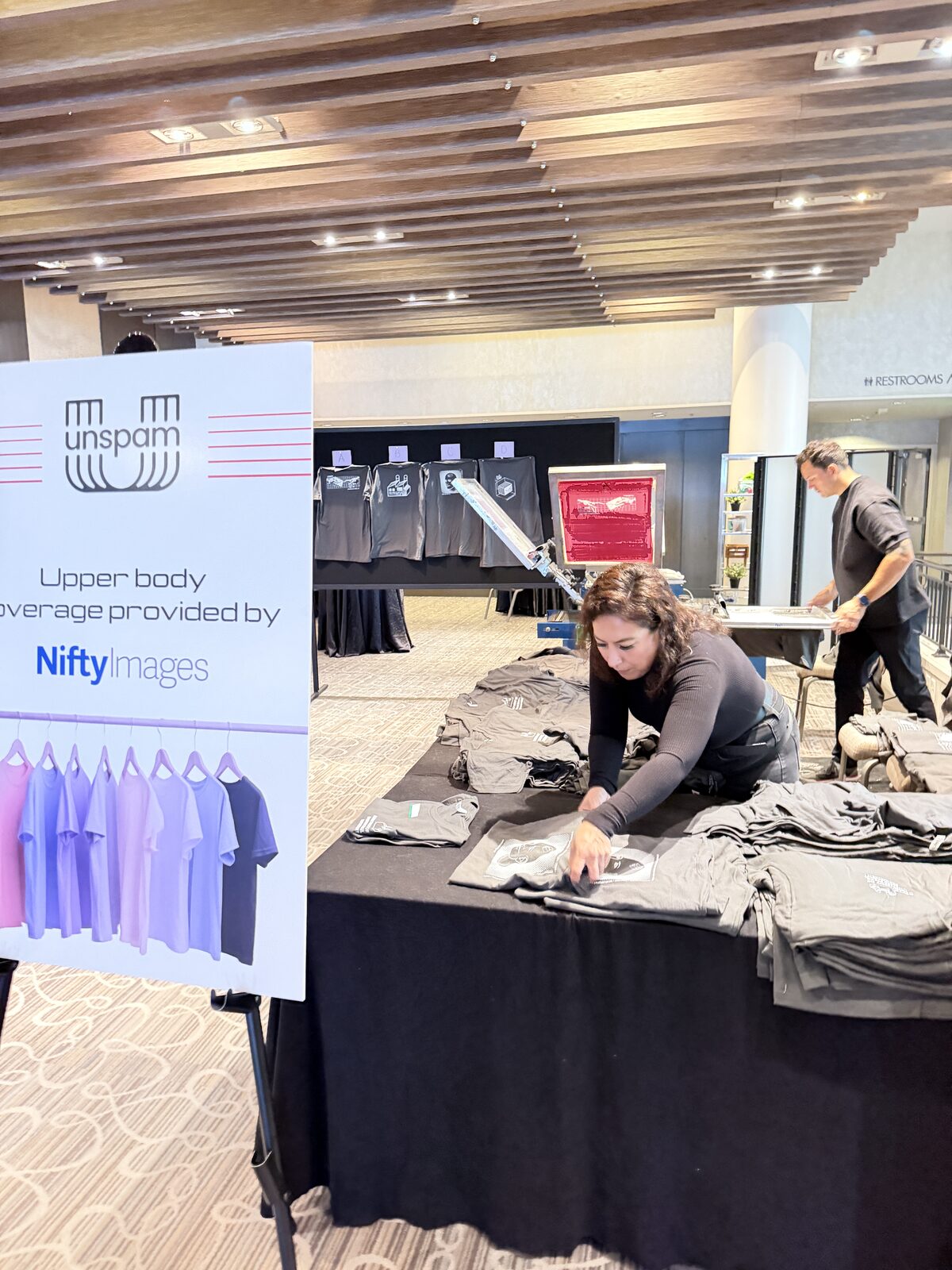 Folded custom shirts stacked across a staffed merch table